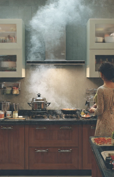 Realistic modular kitchen in an Indian home showing heavy Indian cooking with pressure cooker, tadka, spices, and chimney in use, highlighting whether modular kitchens are suitable for Indian cooking in 2026.